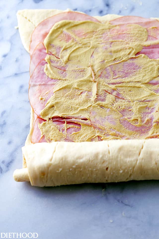 Ham slices arranged over dough and topped with dijon mustard.