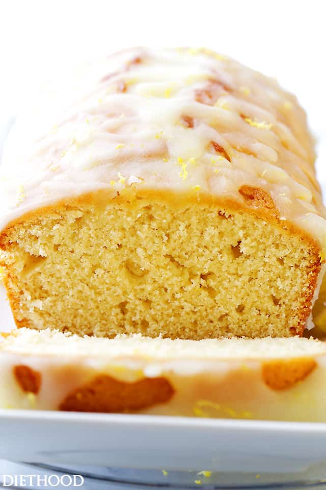 loaf of lemon bread with one slice cut to expose the inside of the quick bread.