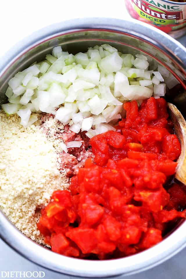 Diced onion, tomato, ground beef and other meatloaf ingredients in a pot.