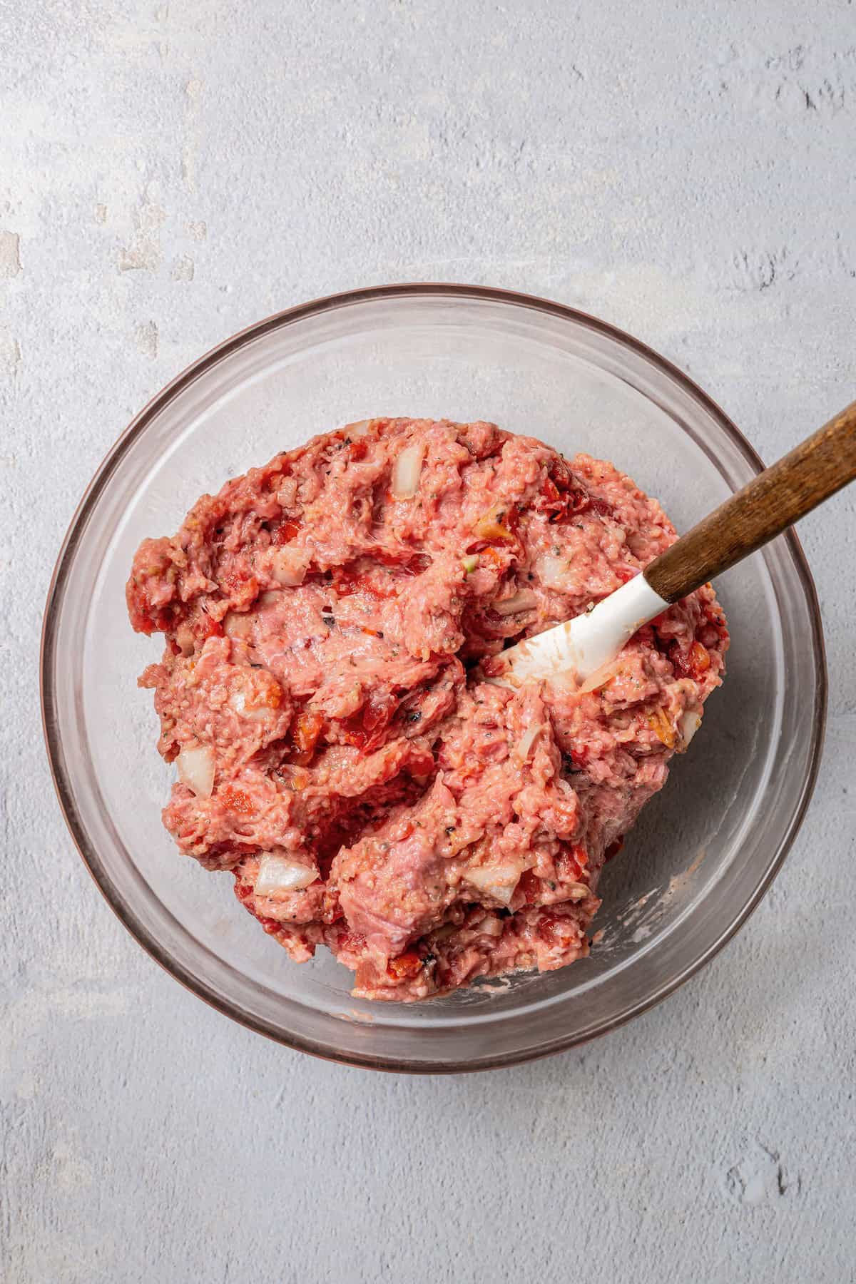 Turkey meatloaf mixture in a glass bowl with a spatula.