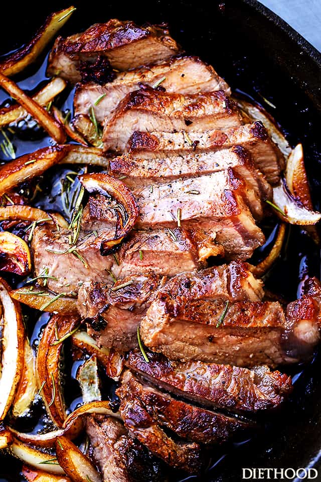 Close up of a sliced pan seared steak in a cast iron skillet topped with caramelized onions.