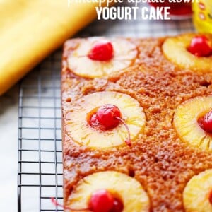 A whole Pineapple Upside Down Cake with cherries and pineapple on top of a wire rack