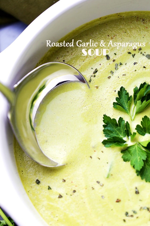 Roasted Garlic and Asparagus Soup in a white soup pot and a stainless steel ladle inside the soup