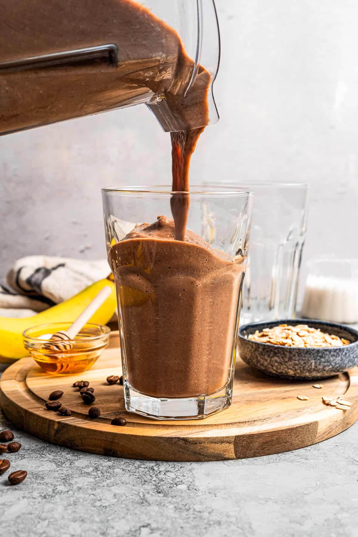 Pouring a smoothie from a blender and into a drinking glass.