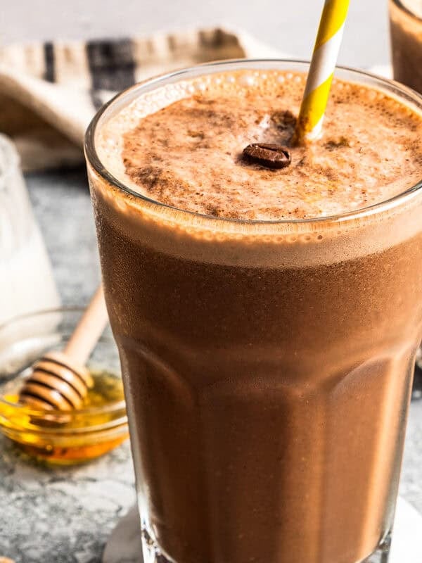A coffee smoothie in a tall glass with a straw.