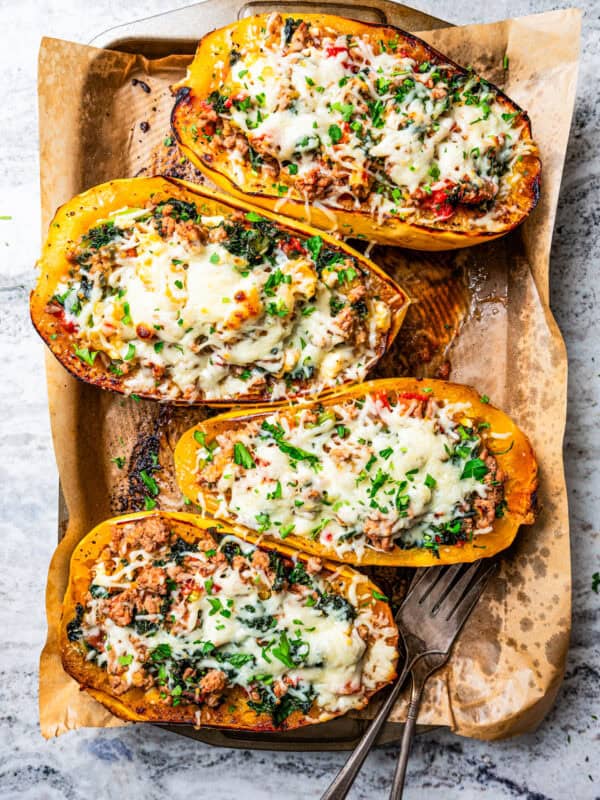 Baked spaghetti squash boats topped with melted mozzarella cheese in a baking pan.