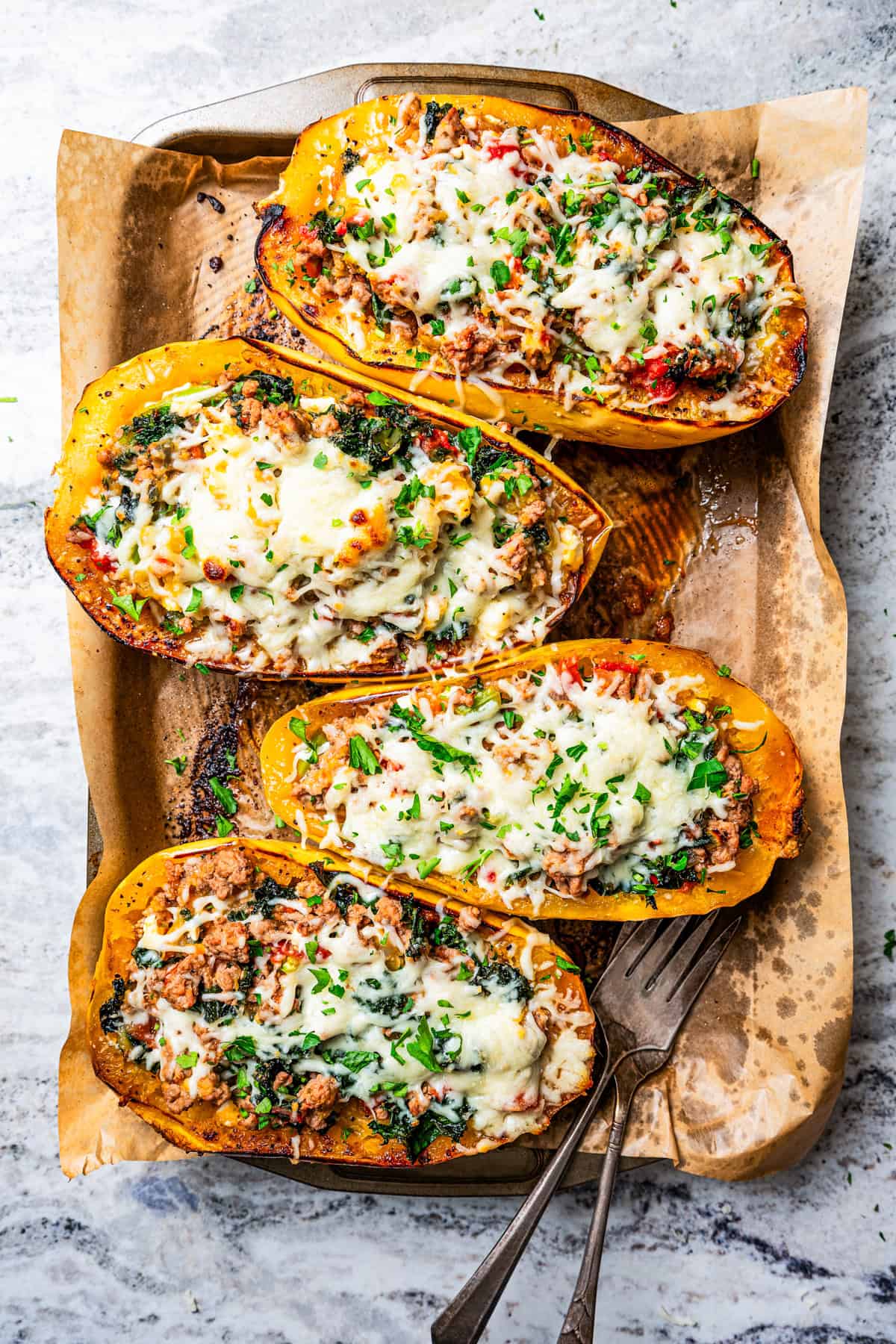 Baked spaghetti squash boats topped with melted mozzarella cheese in a baking pan.