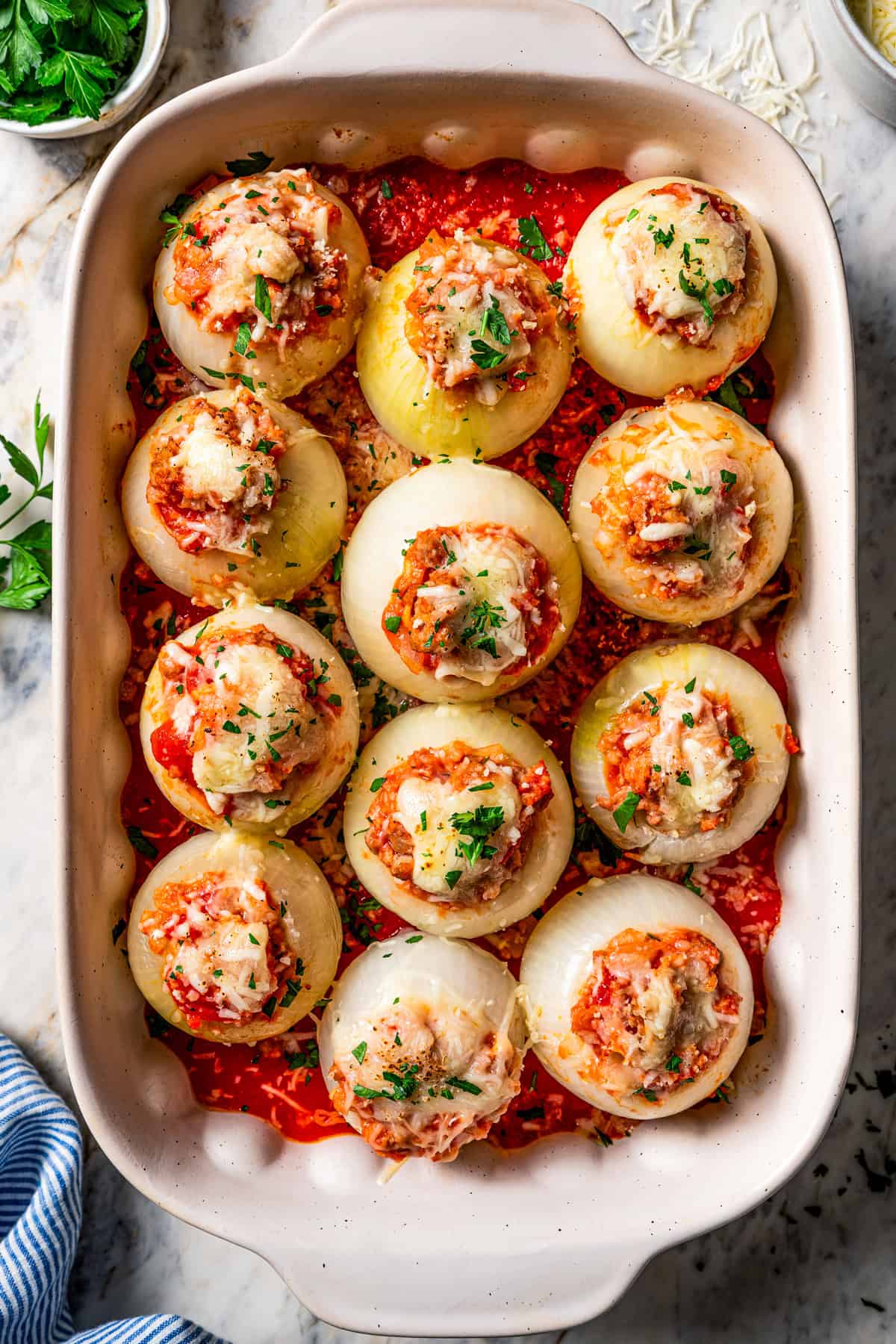 Overhead view of stuffed onions inside a baking dish.