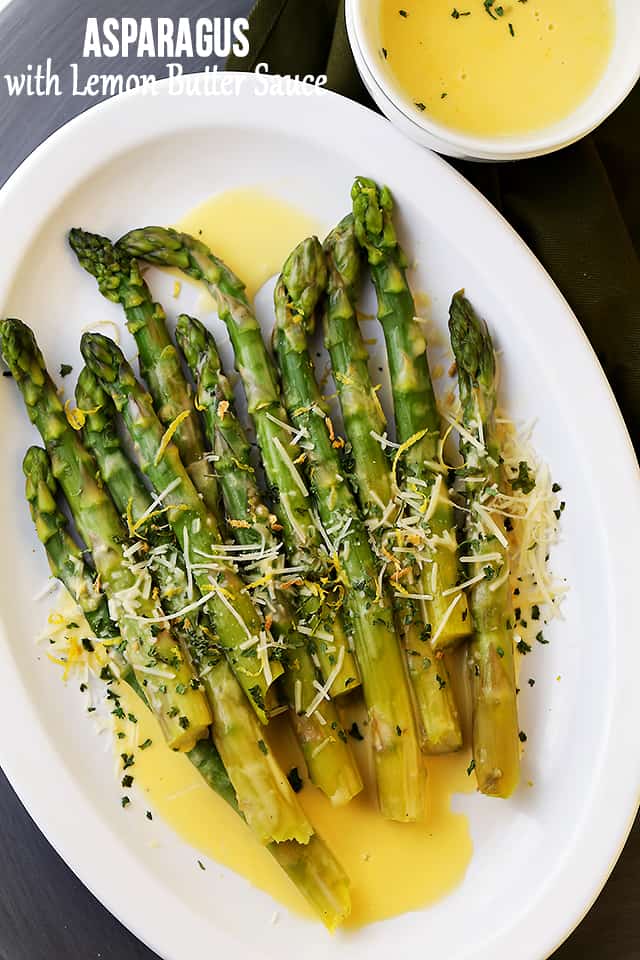 Asparagus served on an oval platter and topped with lemon butter sauce.