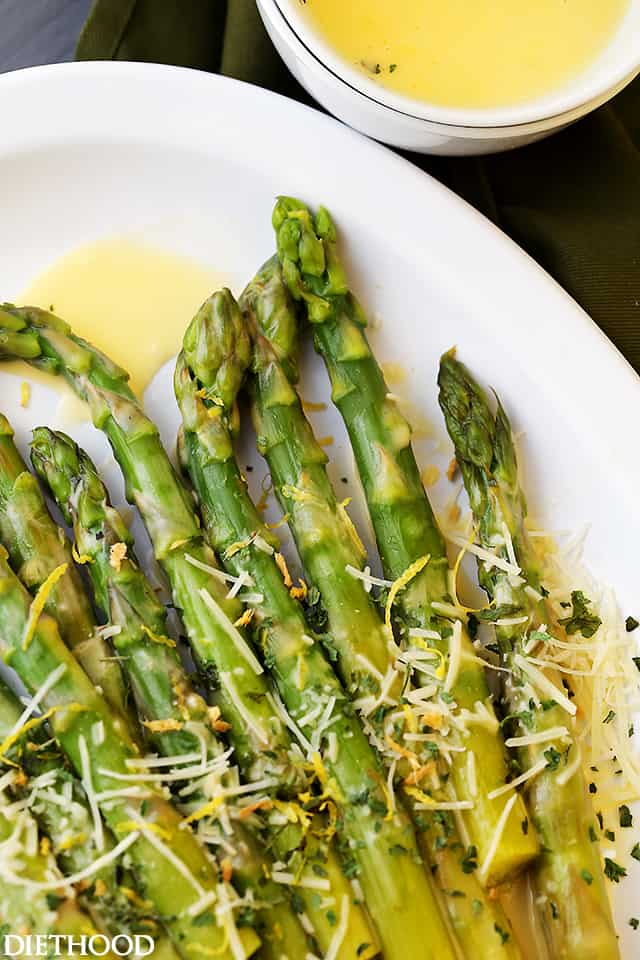 Asparagus with Lemon Butter Sauce served on a platter and topped with shredded parmesan, lemon zest, and chopped parsley.