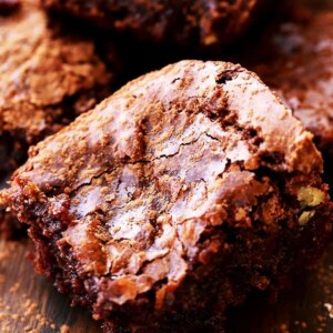 Close up of a fudgy brownie with more brownies stacked in the background.