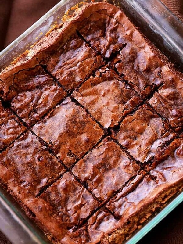 Overhead view of a baking tray of fudgy brownies cut into squares.