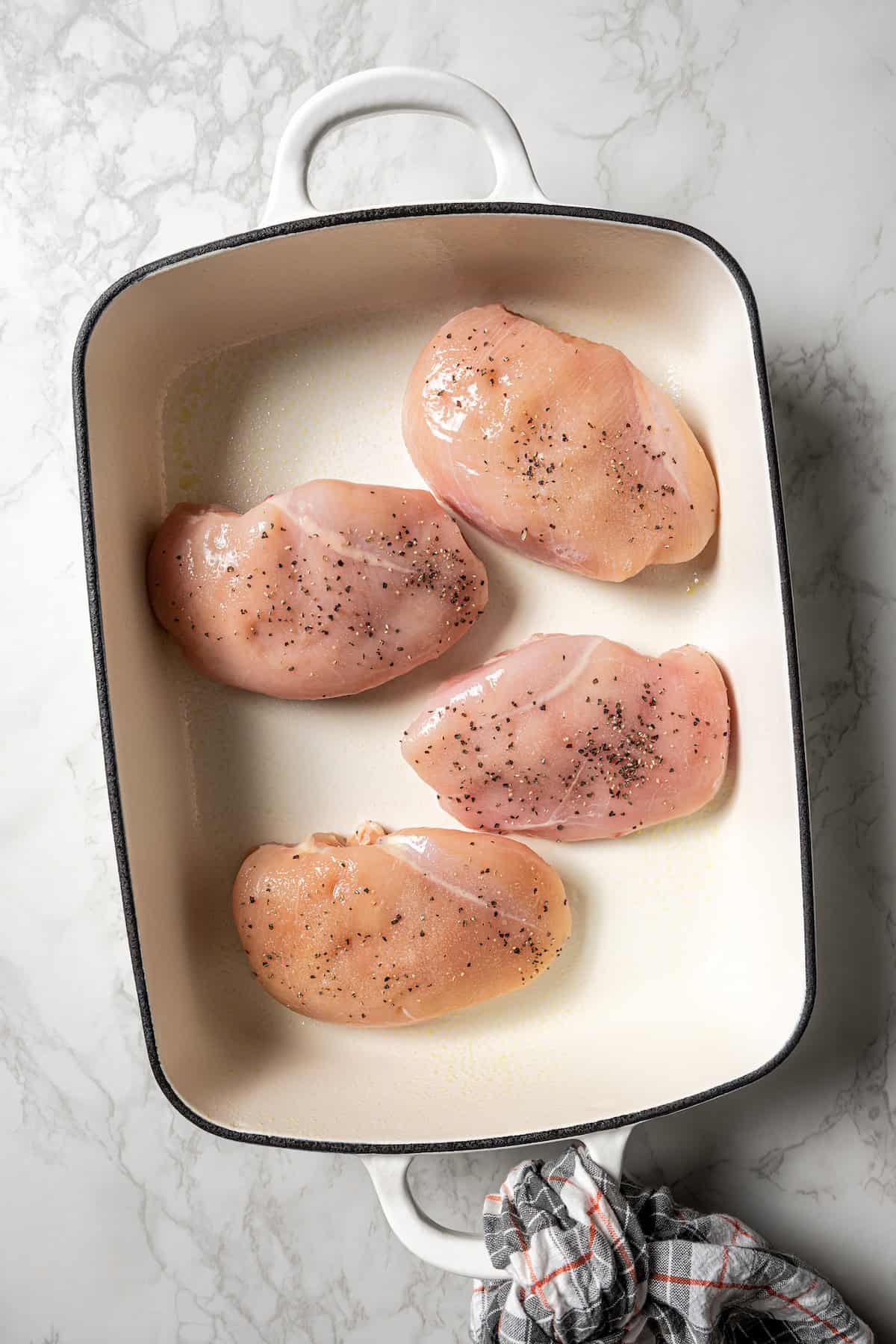 Seasoned chicken breasts inside a ceramic baking dish.