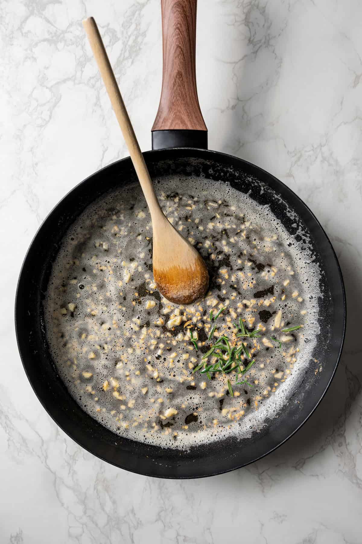 Minced garlic sautéeing in a skillet with melted butter.