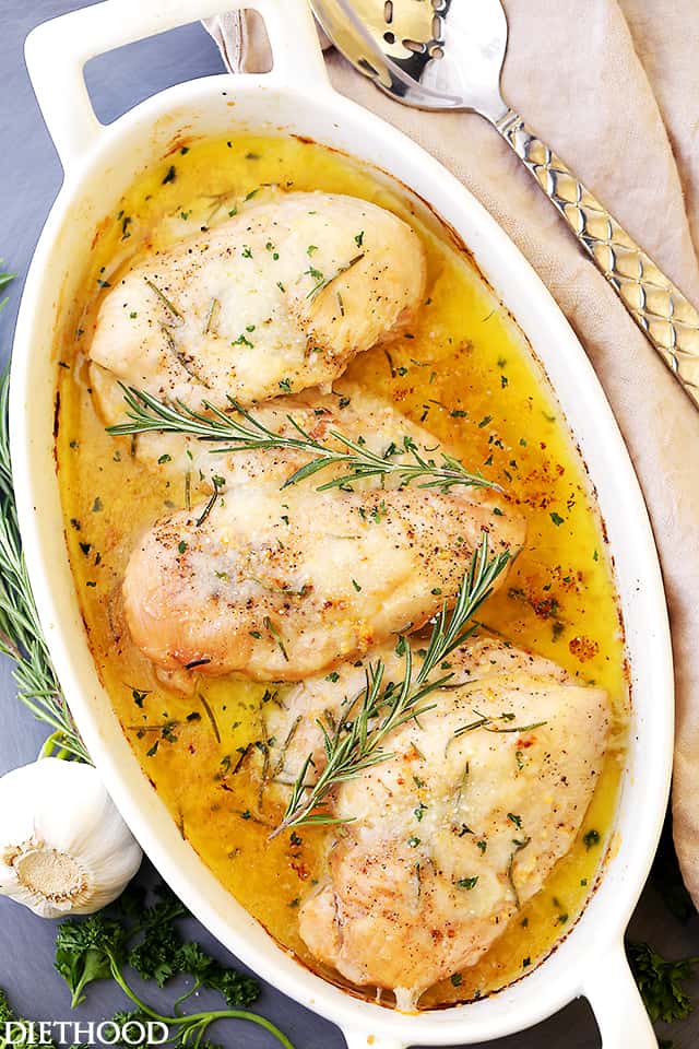 An overhead shot of three baked garlic butter chicken breasts in a baking dish.