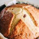 A loaf of Irish soda bread in a parchment-lined cast iron skillet.