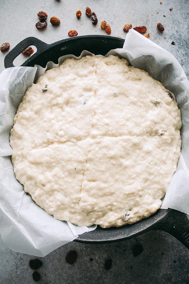 Soda bread dough tucked into a parchment-lined cast iron skillet.