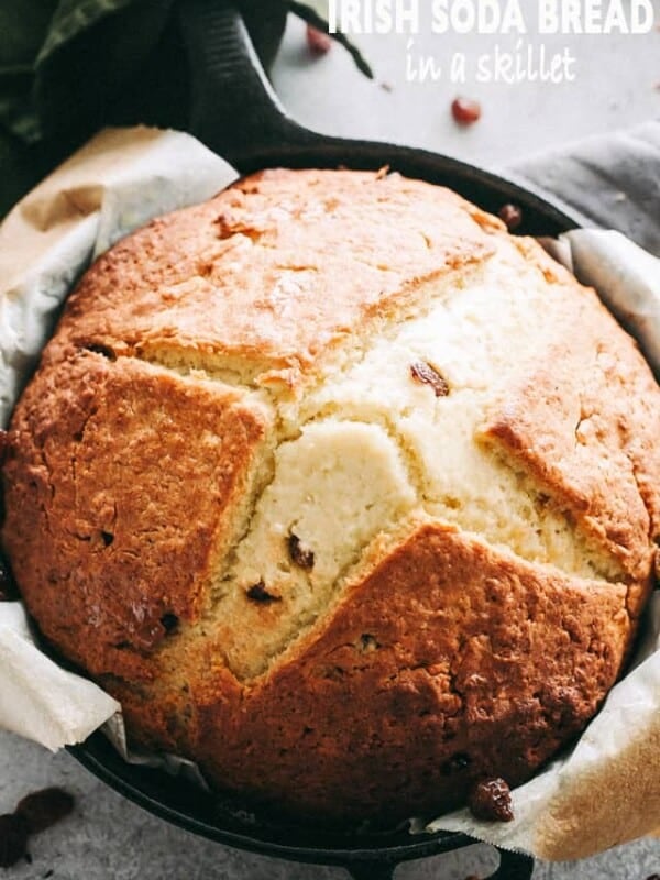 A loaf of Irish soda bread in a parchment-lined cast iron skillet.