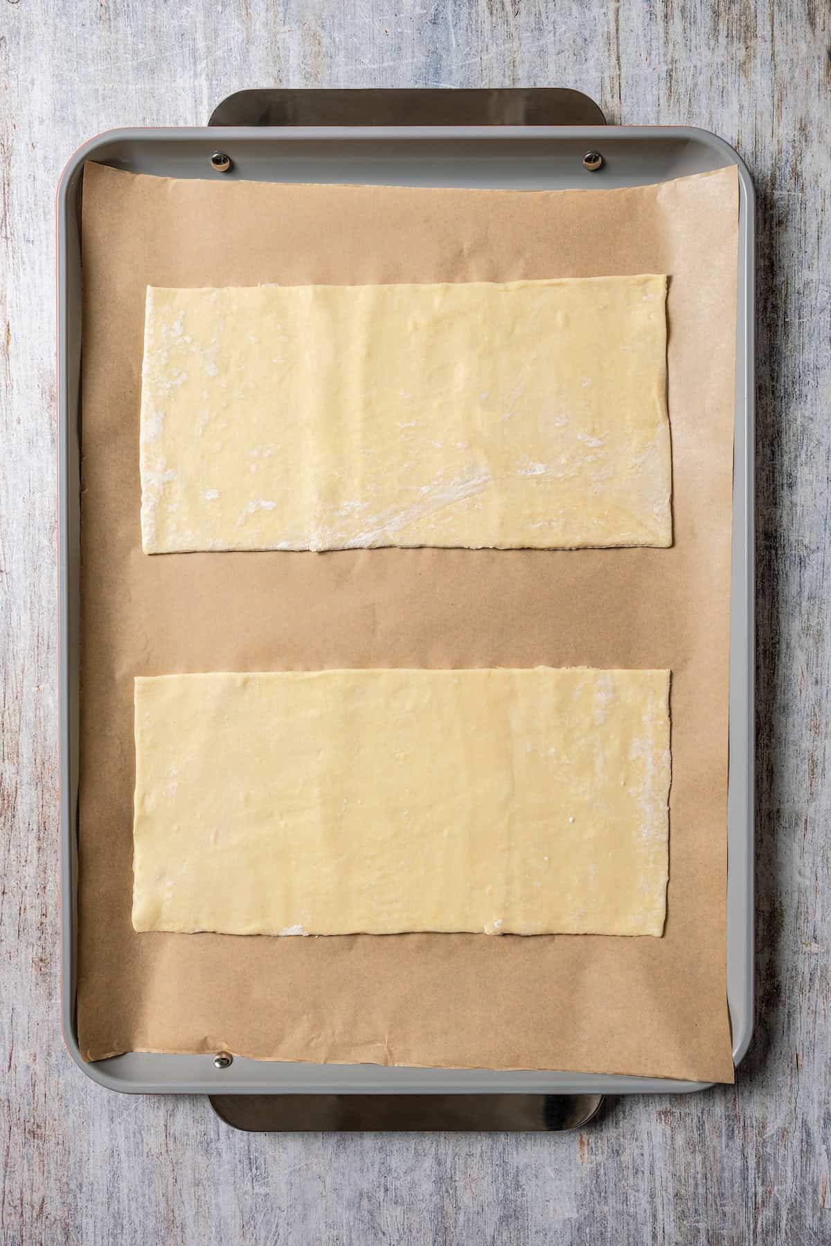 Two rectangular puff pastry sheets on a parchment-lined baking sheet.