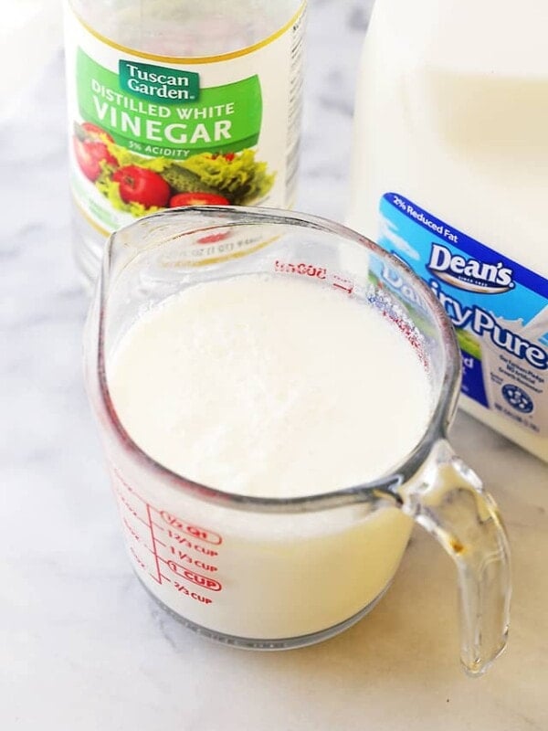 Milk combined with vinegar in a glass measuring cup.