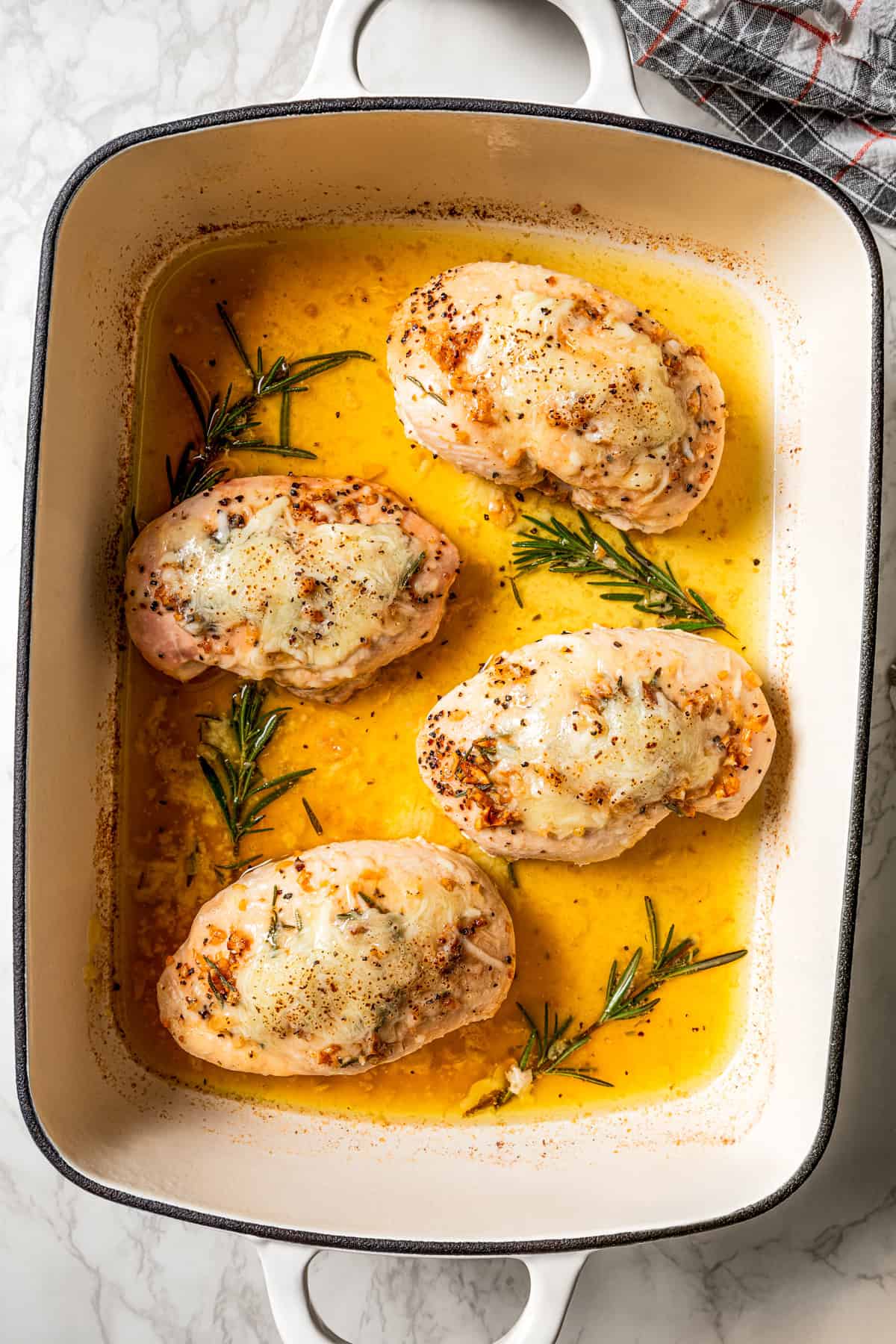 Four baked chicken breasts in a baking dish.