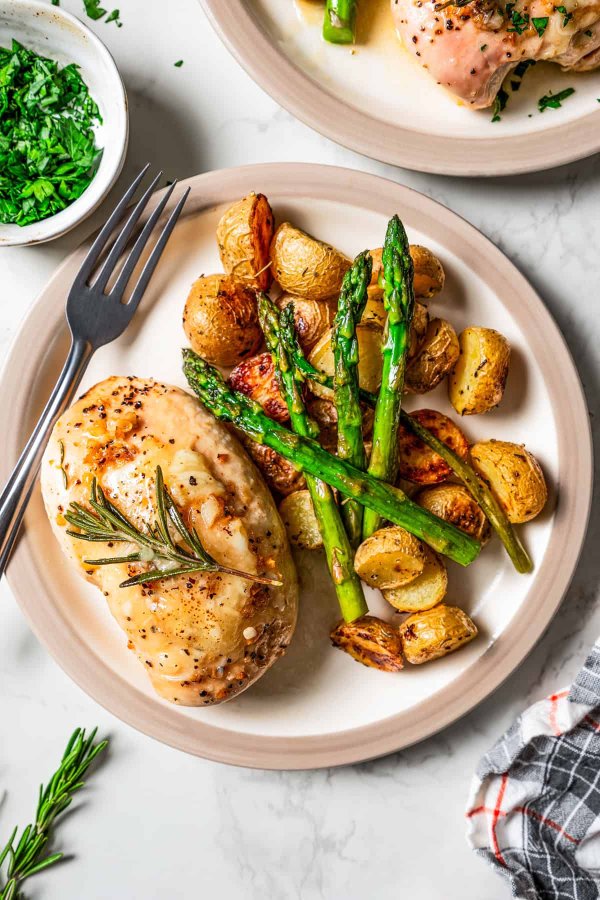 Garlic butter chicken served on a plate with roasted potatoes and asparagus.