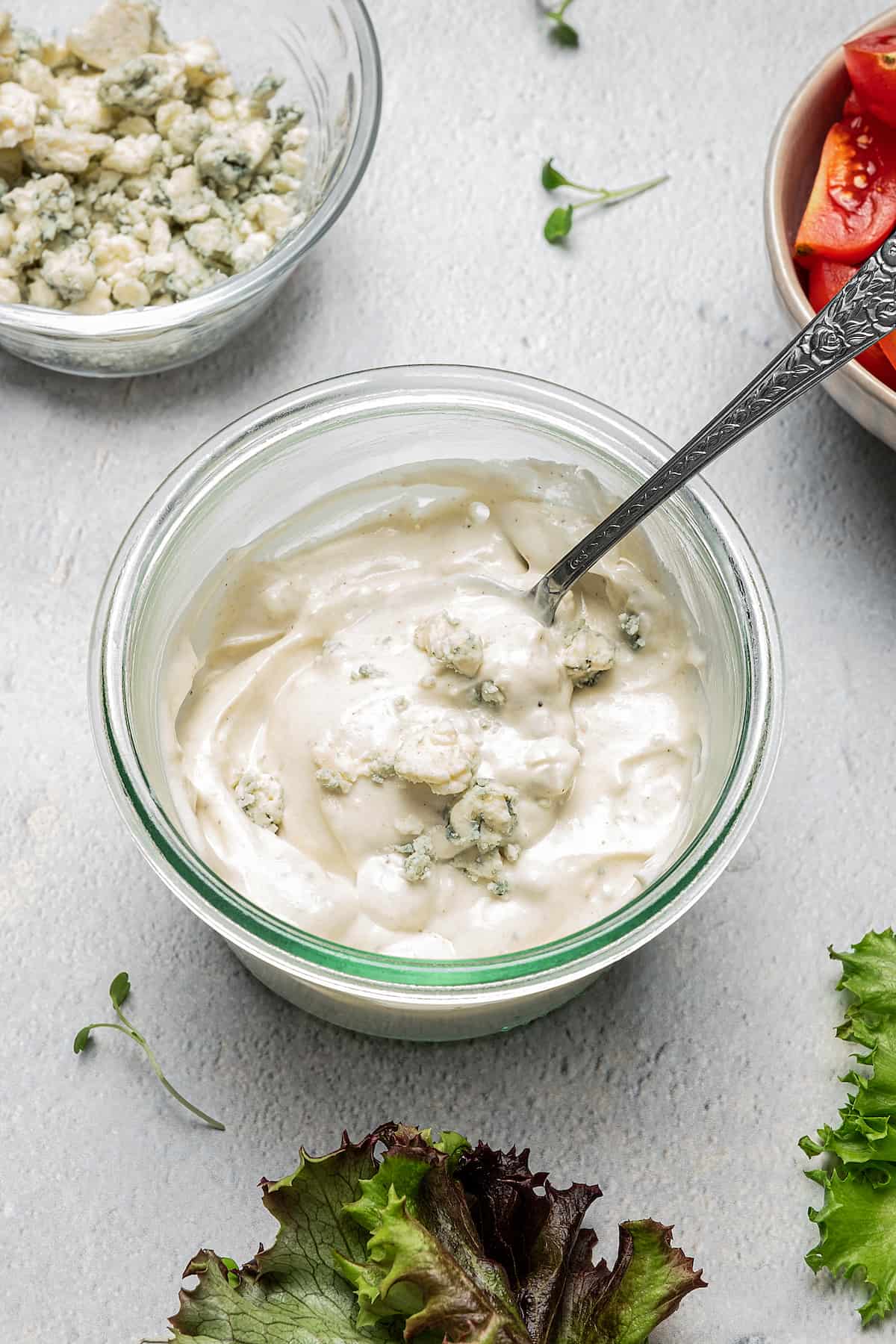 Blue cheese dressing in a glass bowl with a spoon.