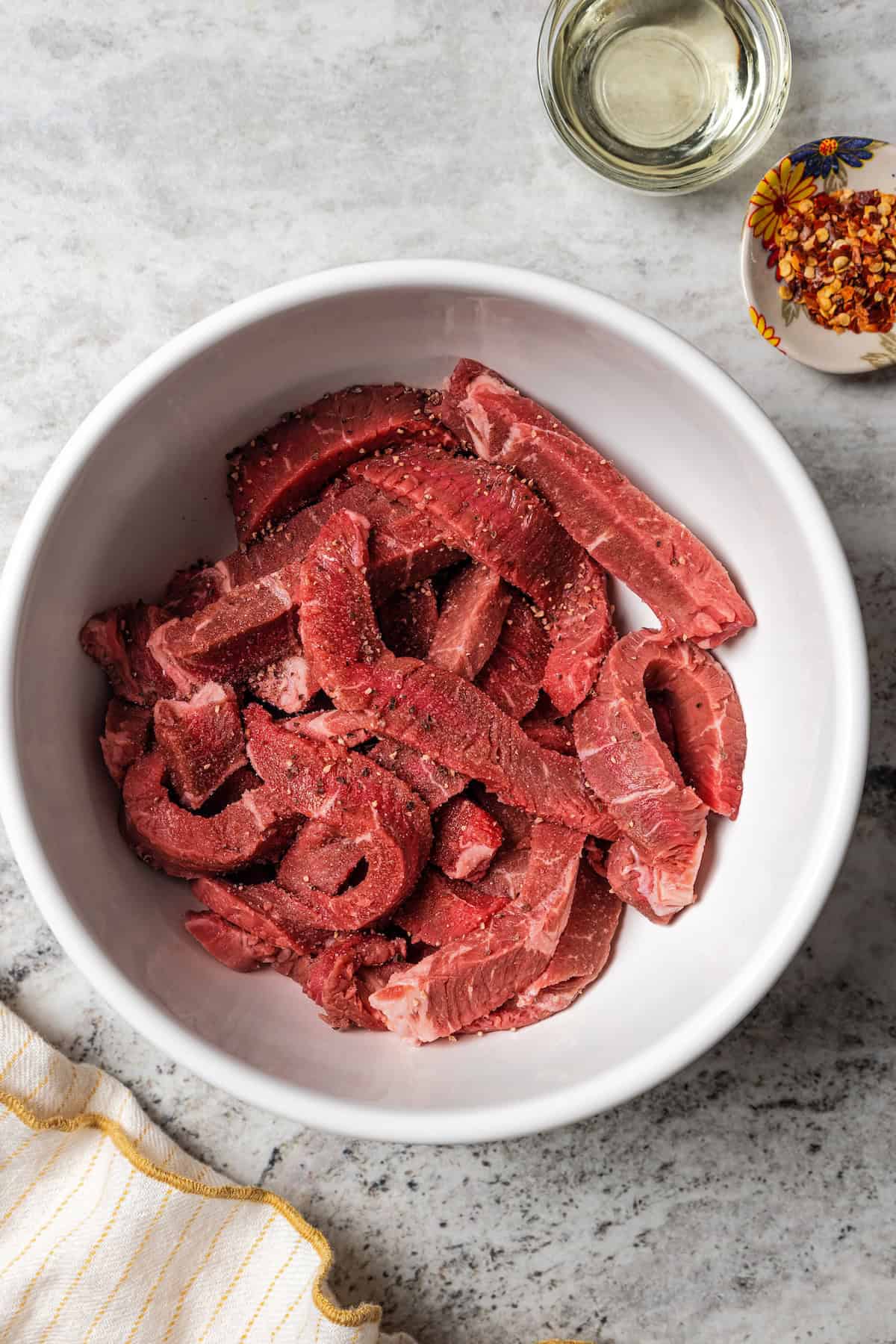 Seasoned beef strips in a bowl.