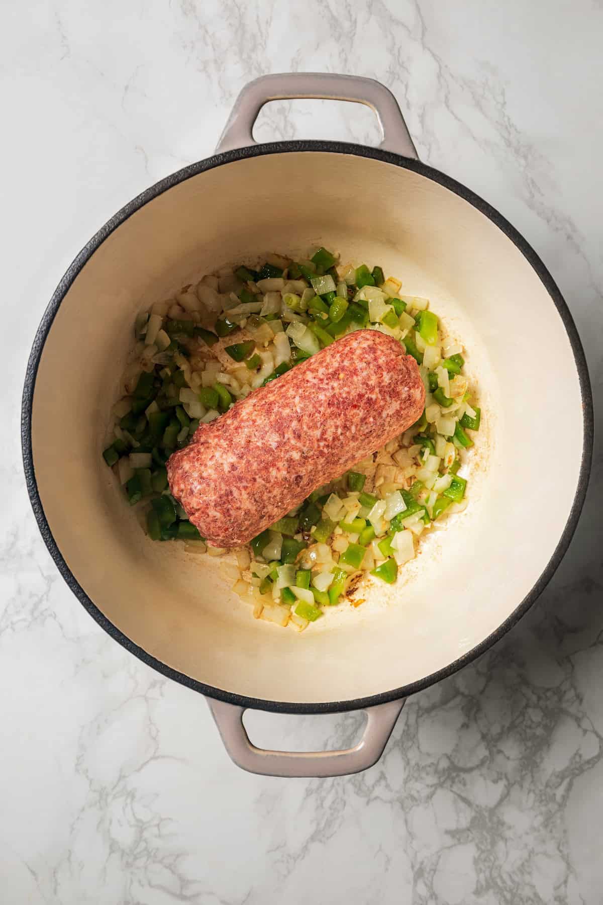 Pork sausage added to a large pot with sautéed onions and green peppers.