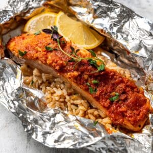 Salmon and rice in an open foil packet garnished with lemon wedges.