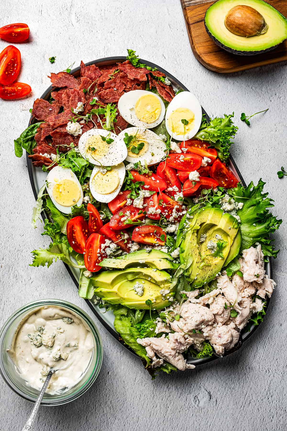 Overhead view of a homemade Cobb salad next to a small bowl of blue cheese dressing.