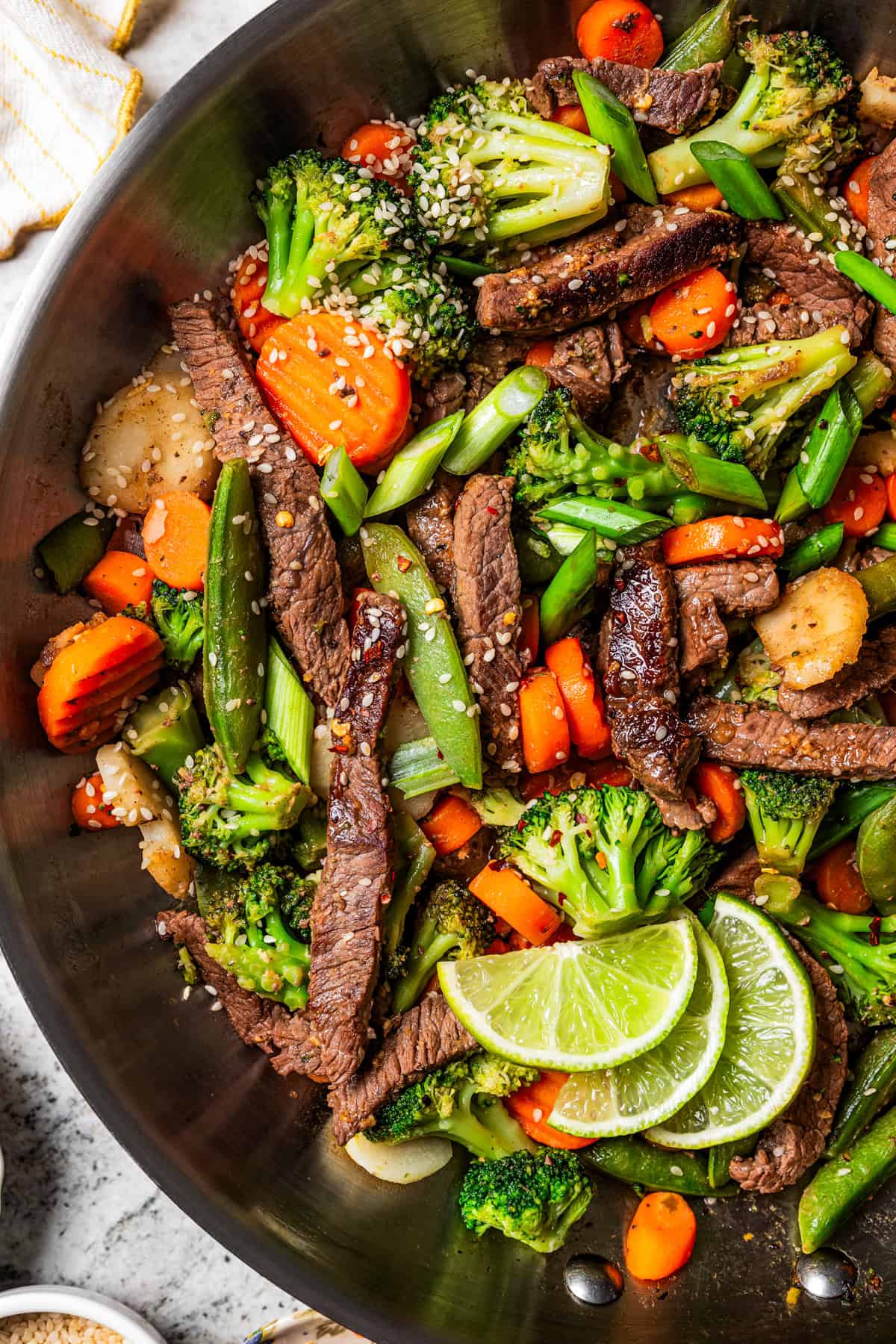 Close-up image of beef stir fry in a large metal skillet.