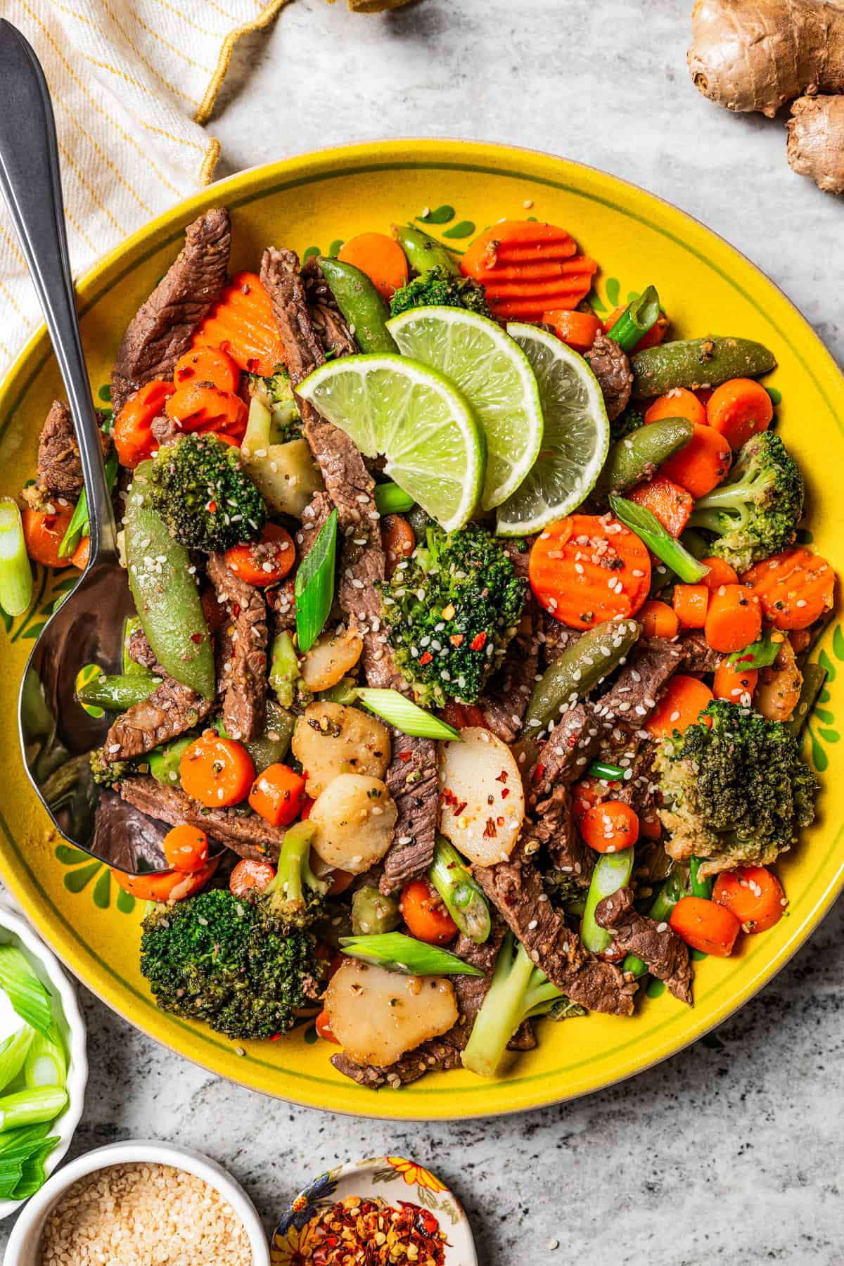 Beef stir fry in a large yellow serving bowl.