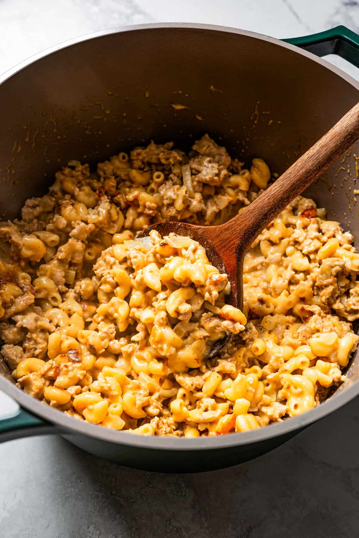 Hamburger Helper in a large pot with a wooden spoon.