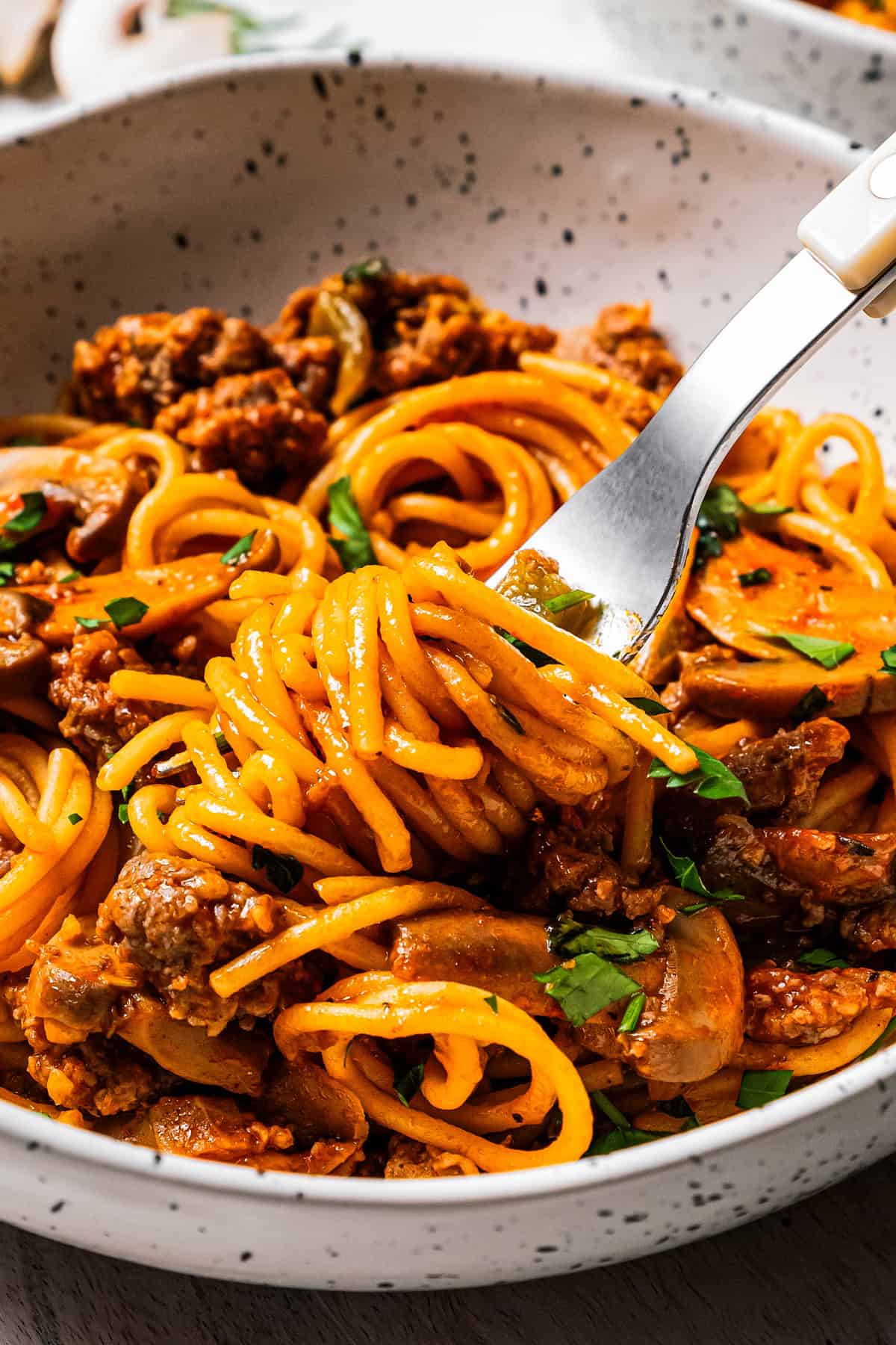 A fork twirling spaghetti from a bowl.