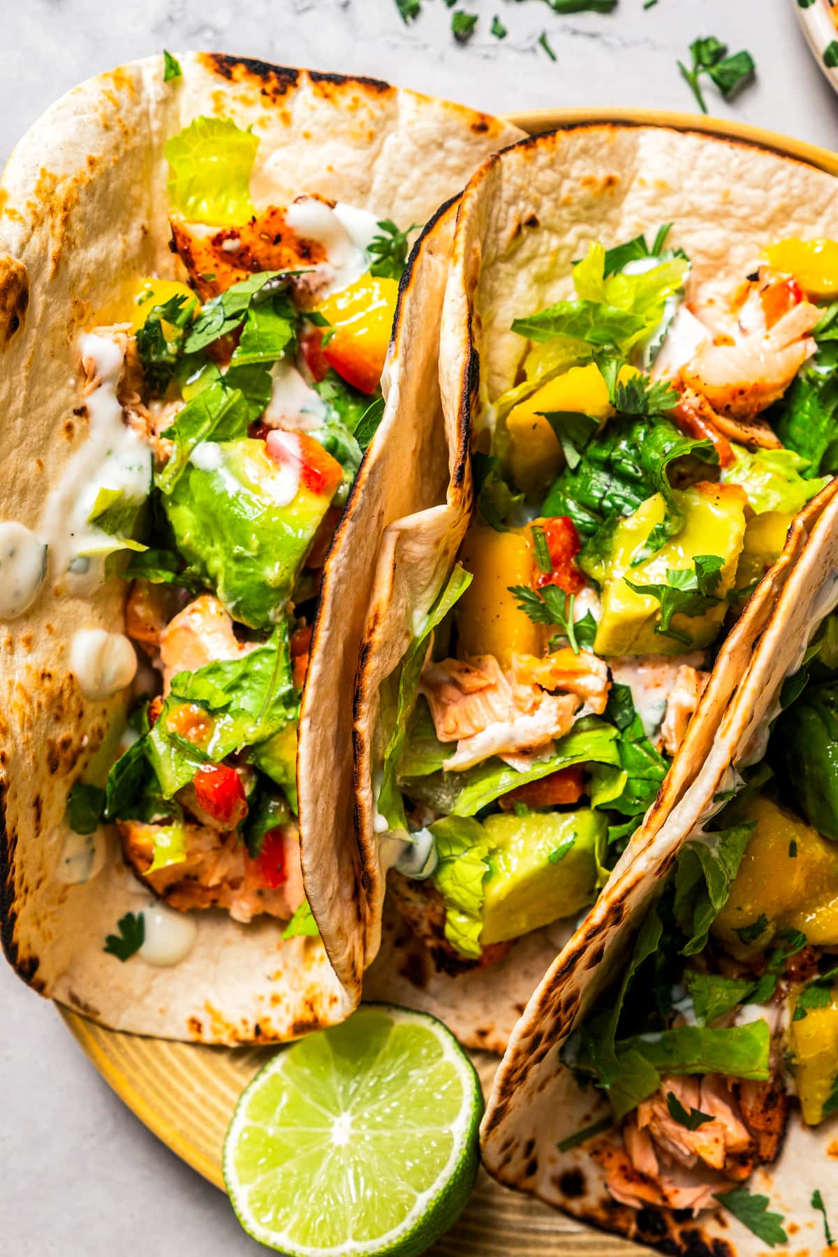 Overhead image of a plate with three tacos with salmon and mango avocado salsa.
