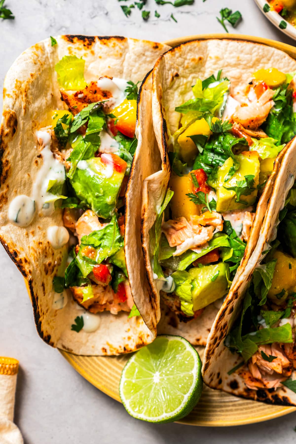 Overhead image of a plate with three salmon and mango avocado salsa tacos.