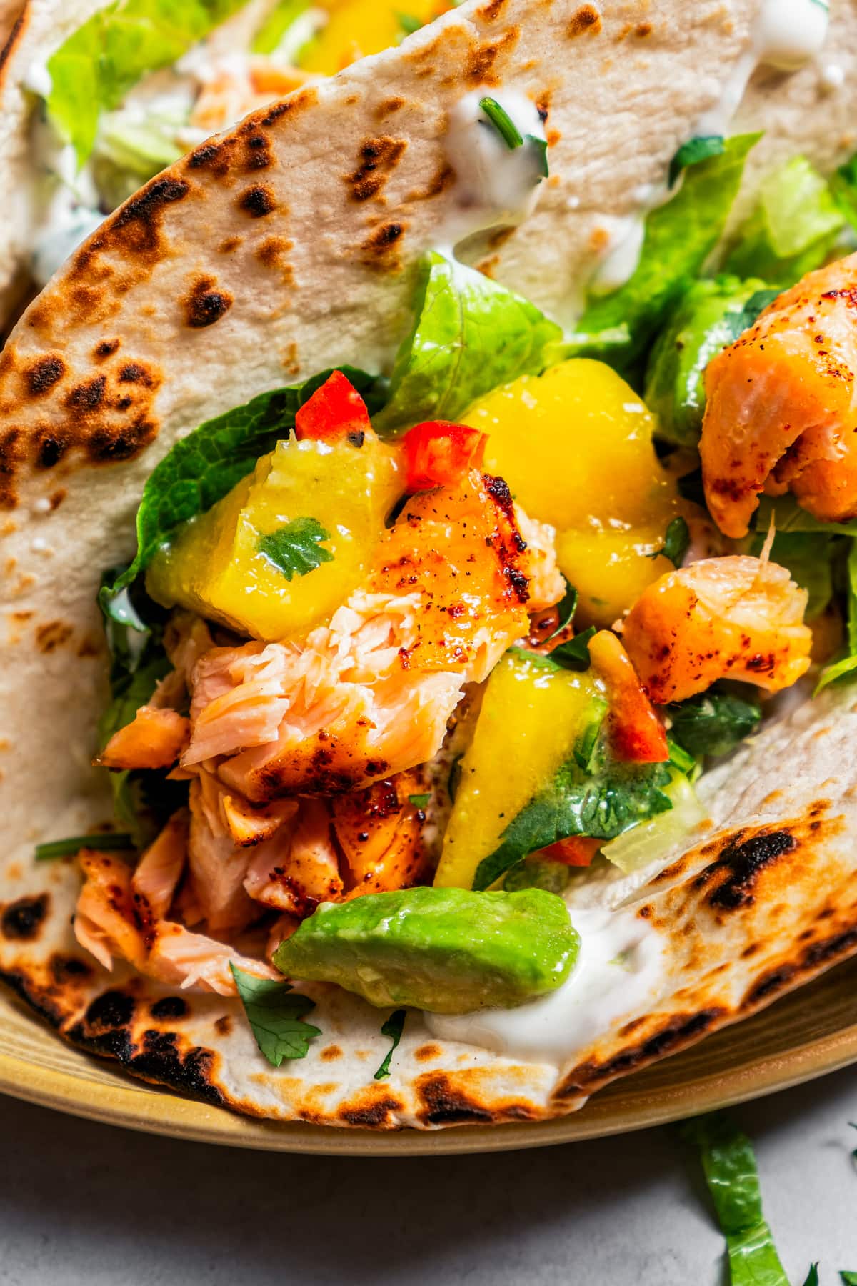 Closeup photo of tacos with salmon and mango avocado salsa.