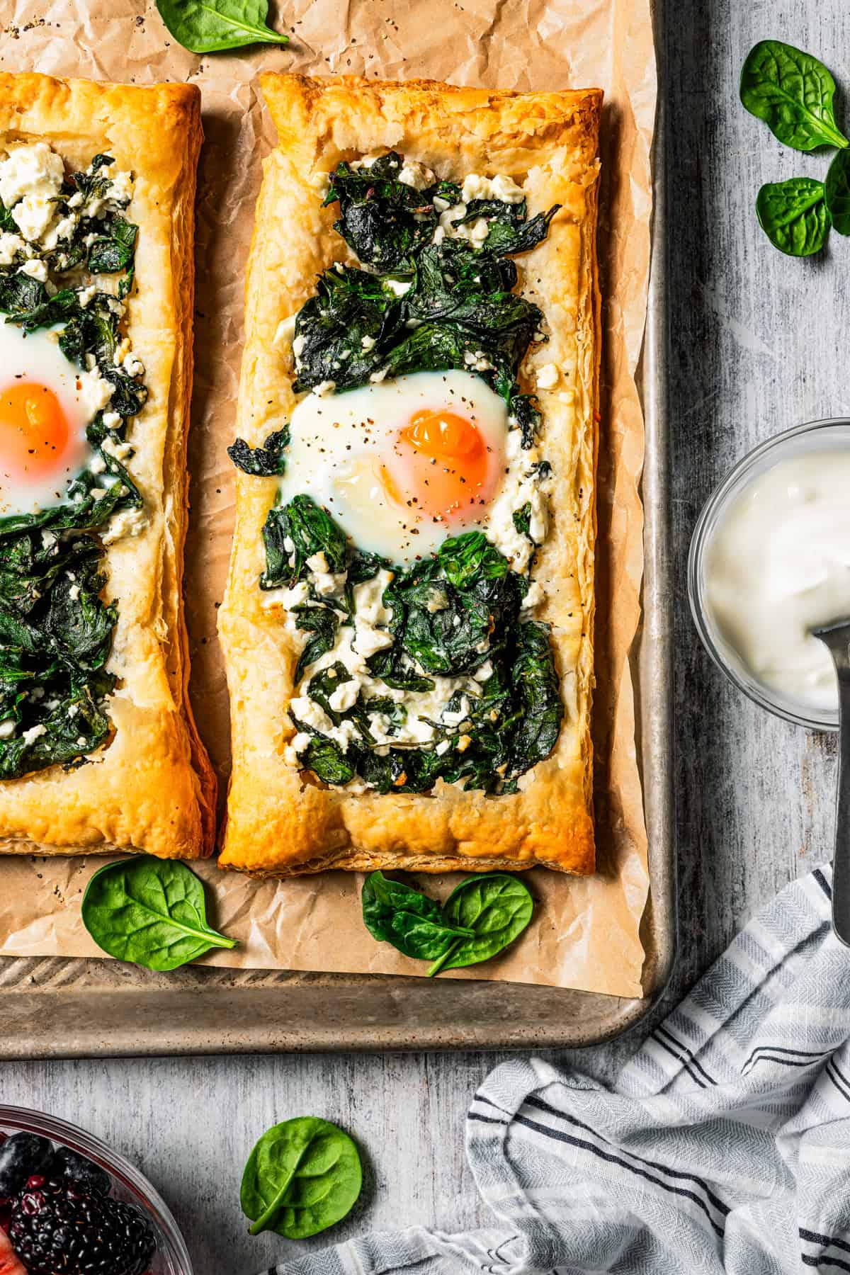 Overhead view of two spinach and feta puff pastries served on a parchment-lined baking sheet.