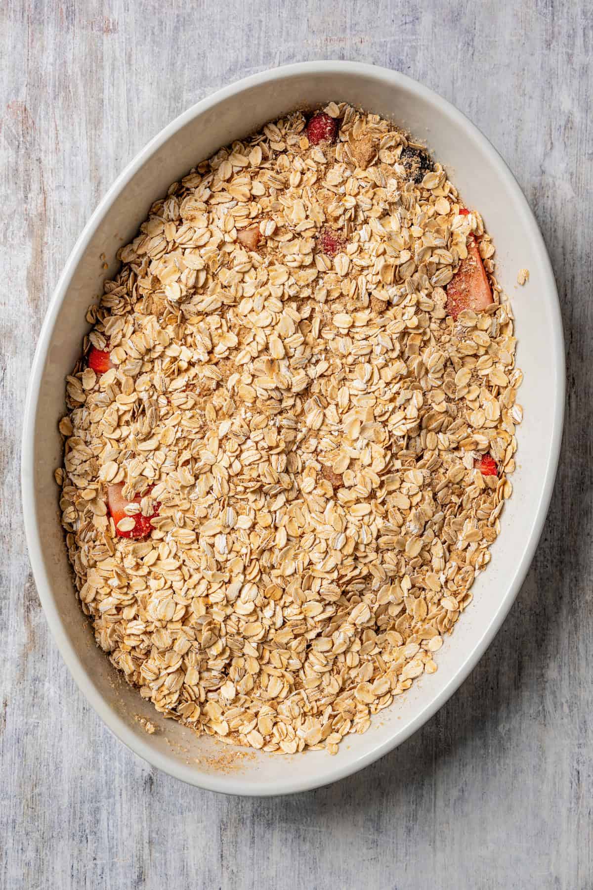 Berries topped with oatmeal in an oval casserole dish.