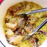A Dutch oven with chicken drumsticks and thighs in coconut milk braising liquid.