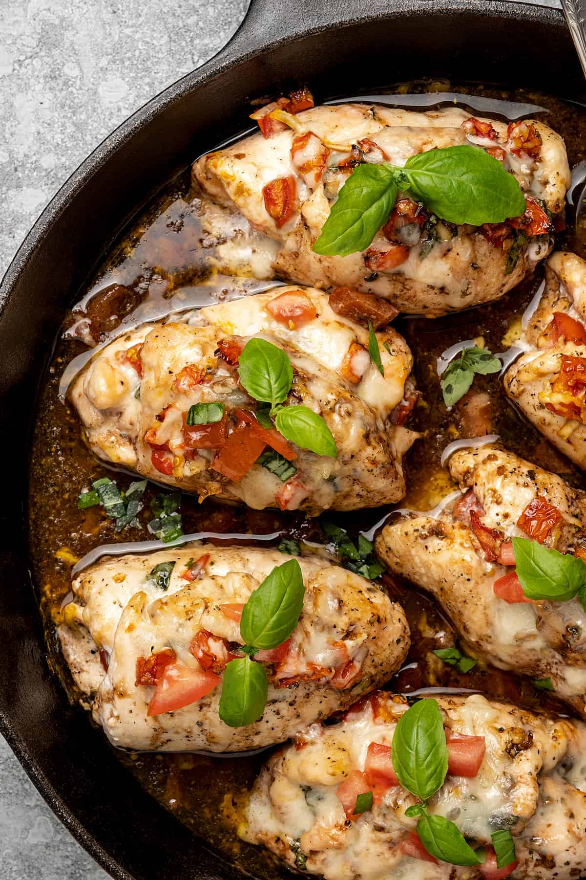 Close up of bruschetta stuffed chicken breasts cooked in a skillet with balsamic sauce.