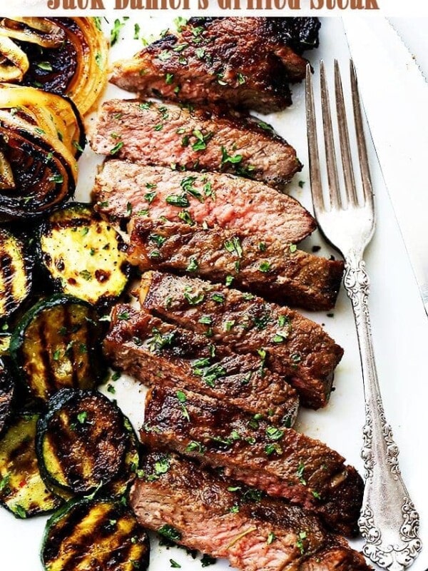 Title image for Jack Daniel's Steak featuring a grilled steak cut into slices next to grilled zucchini and onion on a plate.