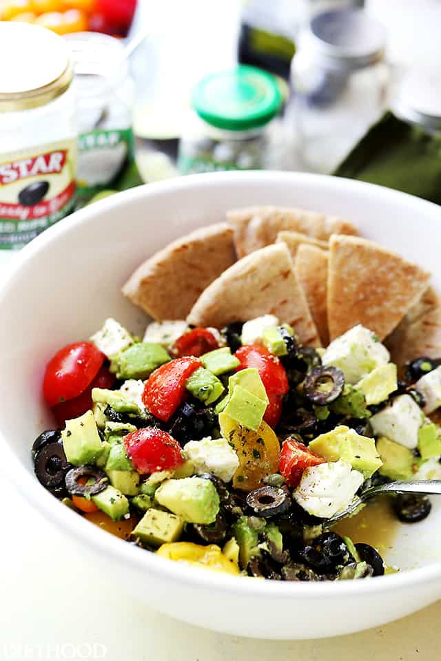 Avocado Salad with Tomatoes and Feta Cheese served in a bowl with pita bread wedges placed around the salad.