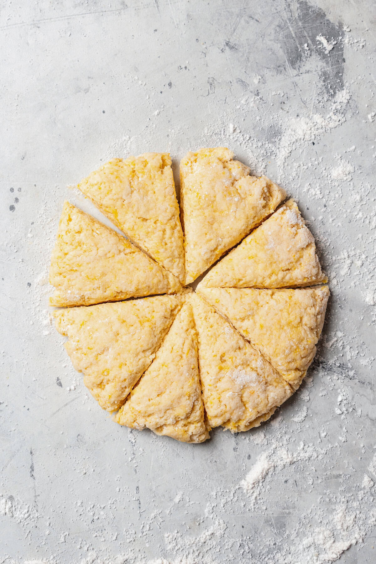 A scone dough disc cut into wedges on a floured surface.