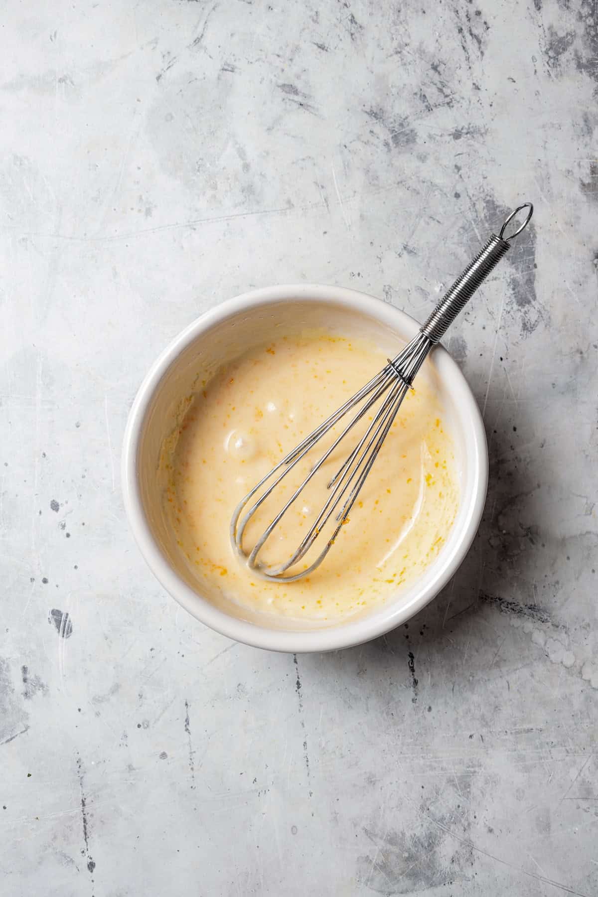 Vanilla glaze in a white bowl with a whisk.