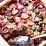 Berry baked oatmeal topped with mixed berries in a baking dish, with one portion served.