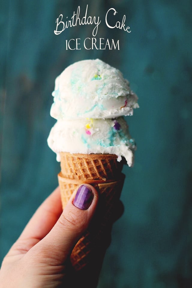 Holding a waffle cone filled with Birthday Cake Ice Cream 