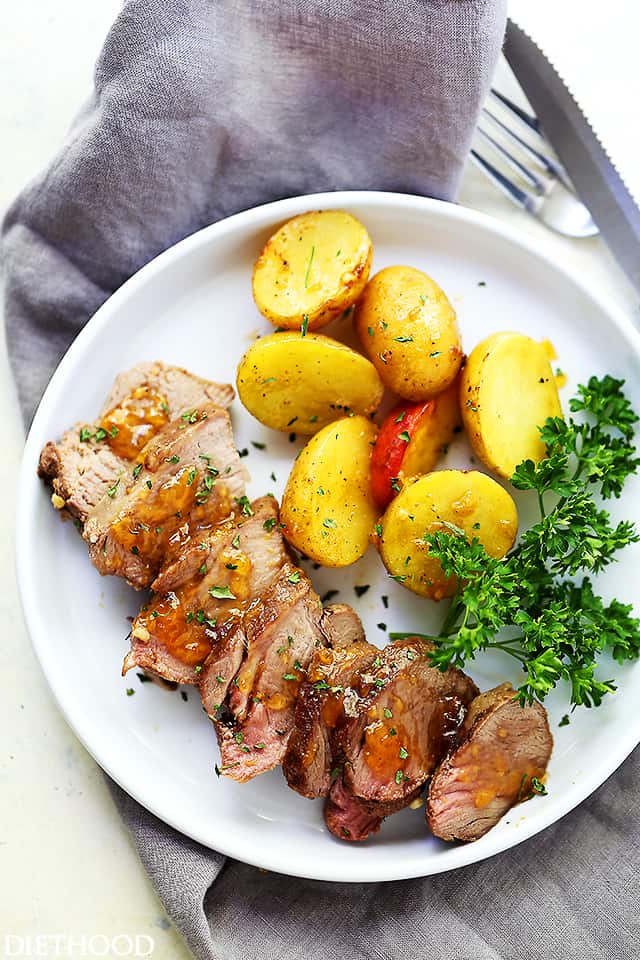 A plate of grilled pork and potatoes on top of a gray kitchen towel