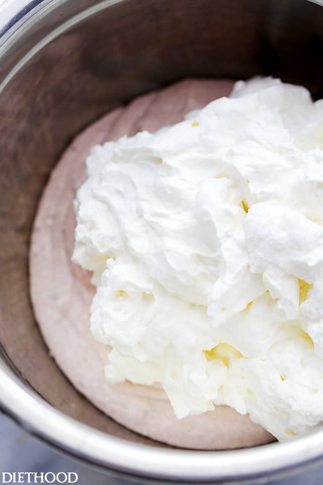 Whipped cream in a bowl with creamed strawberries and jam.